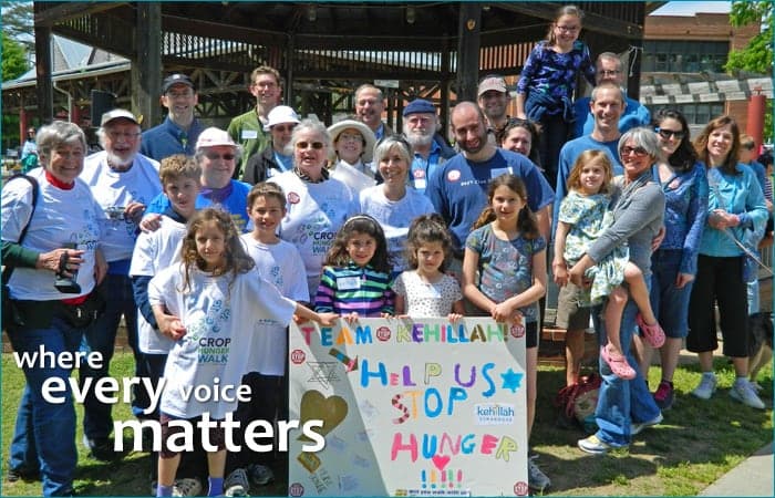 A big group in matching T-shirts at a CROP Hunger Walk with a hand-drawn “Help us stop hunger” sign, and the words “where every voice matters”